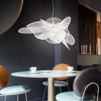 Mesa redonda com cadeiras coloridas e luminária pendente branca em sala escura com pintura abstrata