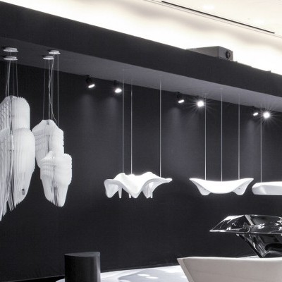 Objetos decorativos suspensos e sobre mesas em espaço moderno, texto DONGDAEMUND na parede.