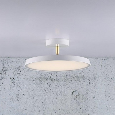 Candeeiro de tecto redondo branco com apoio dourado em parede de cimento