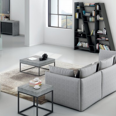 Sala moderna com sofá cinzento, mesas de centro cinza e preta, estante com livros, tapete bege, piso branco e janela ampla