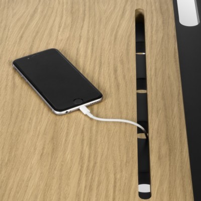 Smartphone preto carregando sobre mesa de madeira com cabo branco