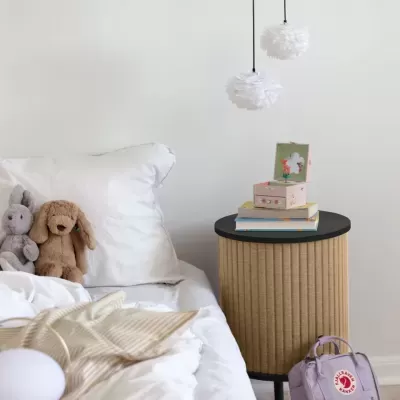 Quarto infantil com cama branca, peluches, mesa de cabeceira e mochila lilás