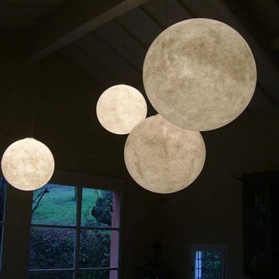 Candeeiros suspensos redondos texturizados e iluminados numa sala com janelas grandes.