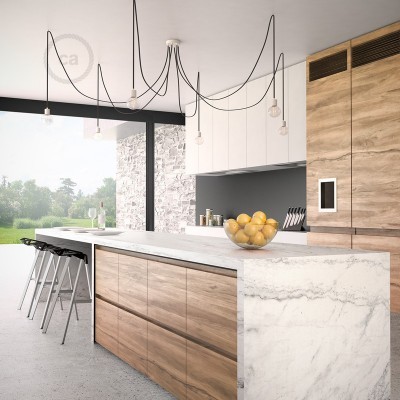 Cozinha moderna com ilha de mármore branco e armários de madeira clara, luminárias pendentes e janela grande com vista para jardim