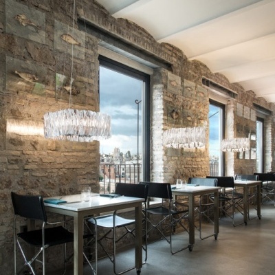 Sala de jantar com mesas brancas, cadeiras pretas e lâmpadas decorativas suspensas