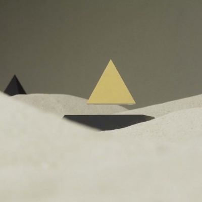 Pirâmide amarela flutuando sobre superfície branca com pirâmides negras ao fundo