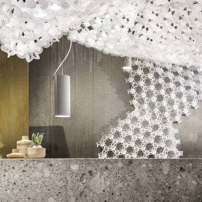 Espaço interior decorado com teto branco entrelaçado, luminária suspensa e balcão de pedra cinzenta