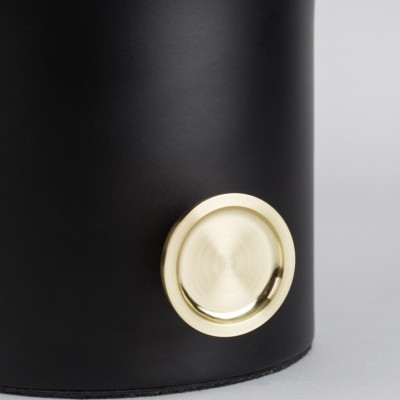 Recipiente cilíndrico preto com botão dourado redondo próximo à base