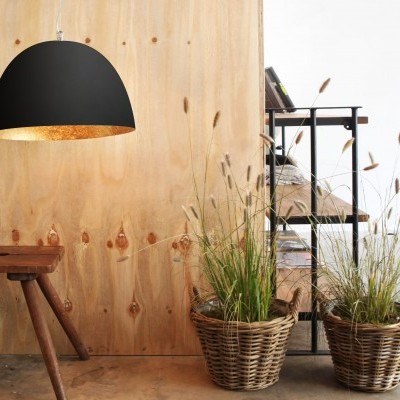 Lâmpada preta pendente, banco de madeira, plantas em vasos de vime e estante preta com livros