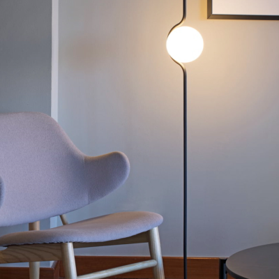 Cadeira cinza de madeira ao lado de candeeiro de pé com lâmpada branca e mesa preta