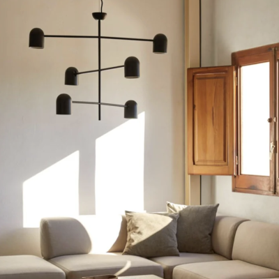 Luminária de teto preta em sala de estar com sofá creme, almofadas cinza, mesa de pedra e janela de madeira