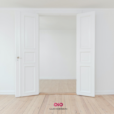 Porta dupla branca aberta para divisão branca com chão de madeira clara e logótipo LUX DESIGN no chão