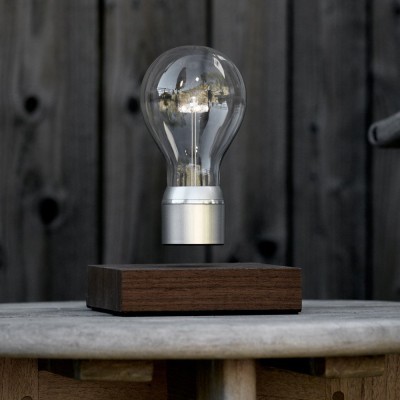 Lâmpada flutuante em base de madeira sobre mesa de madeira