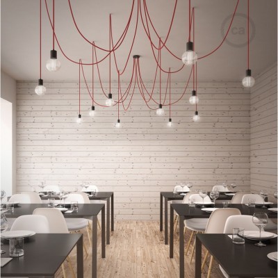 Luminárias suspensas com lâmpadas e cabos vermelhos em sala de restaurante com mesas e cadeiras