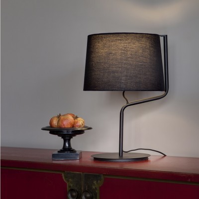 Abajur preto de mesa com cúpula de tecido junto a prato preto com romãs sobre móvel vermelho