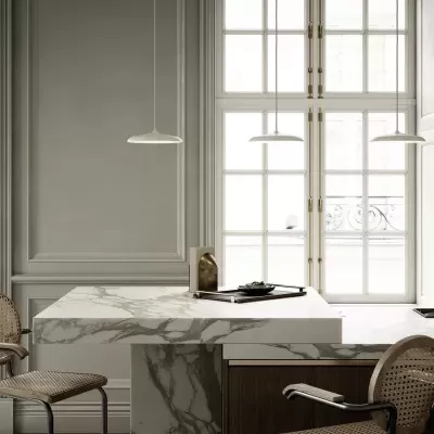 Ilha de cozinha em mármore com cadeiras de palhinha e luminárias pendentes em ambiente minimalista