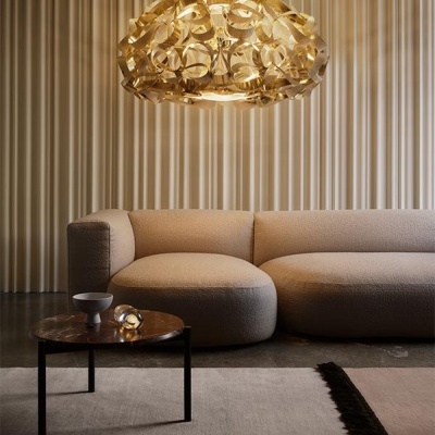 Lustre dourado suspenso, sofá bege texturizado e mesa de centro redonda com base preta