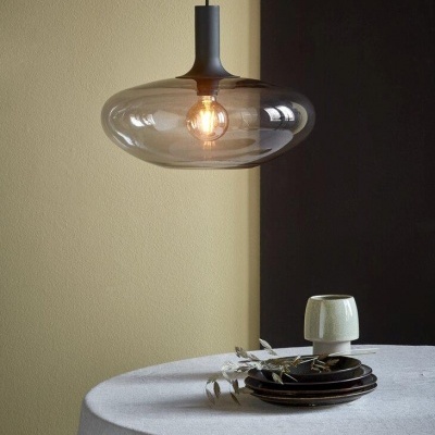 Lustre pendente de vidro fumado transparente sobre mesa com pratos e chávena