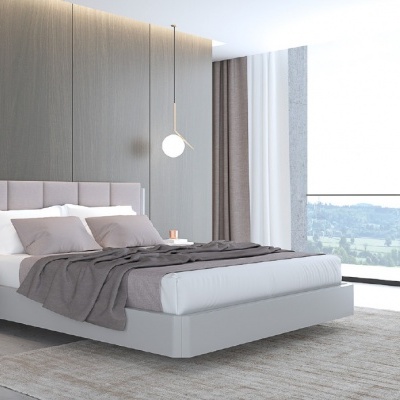 quarto moderno com cama branca e cabeceira creme, mesa de cabeceira cinza com candeeiro, cadeira bege e janela ampla