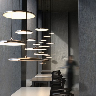 Luminárias pendentes metálicas circulares iluminadas sobre mesa branca em interior cinza