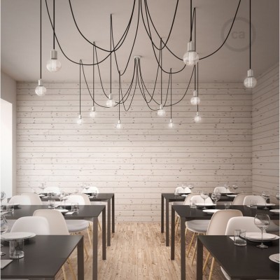 Sala de jantar com mesas pretas, cadeiras brancas, paredes e chão de madeira clara, lustres pendurados