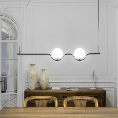 Candeeiro de teto moderno com duas esferas de vidro branco numa sala de jantar com móveis de madeira e parede branca