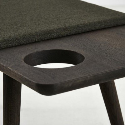 Bancada de madeira escura com assento estofado verde e orifício circular