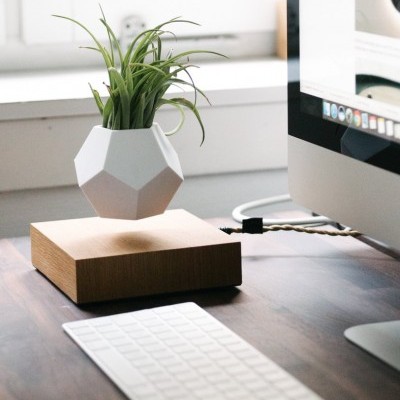 vaso branco geométrico levitando sobre base de madeira numa secretária com teclado e computador