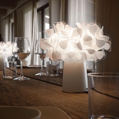 Abajur branco decorativo em mesa de madeira com copos e taças de vidro