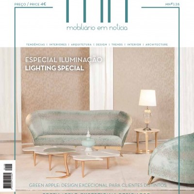 Revista mobiliário em notícia edição especial iluminação com sofá azul claro, mesa de centro e abajur numa sala