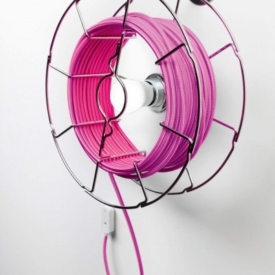 Cabo elétrico rosa enrolado num suporte metálico circular na parede