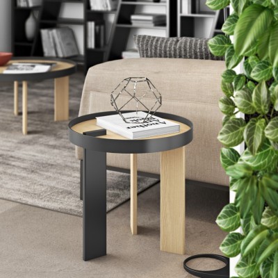 Mesa de apoio redonda com tampo transparente, pernas em madeira clara e metal preto, livro com texto 'FASHION' e objeto decorativo metálico