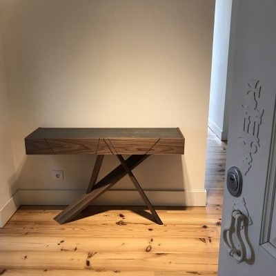 Consola de madeira escura com design moderno e legs cruzadas