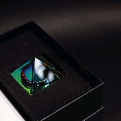 Prisma de vidro com reflexos coloridos numa caixa preta com espuma