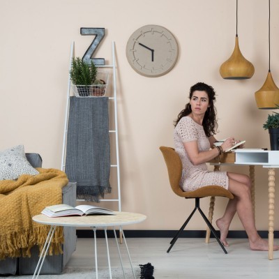 Sala de estar com decoração moderna e mulher sentada numa secretária a escrever