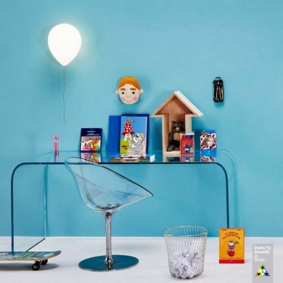 Mesa de vidro com cadeira transparente, balão branco, livros infantis e decoração colorida