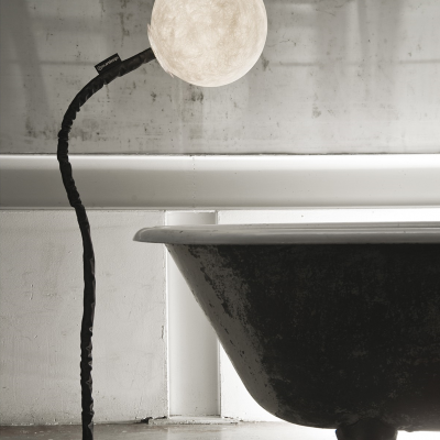 Candeeiro de pé com cúpula redonda que parece a lua ao lado de banheira preta vintage