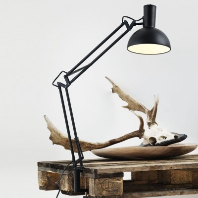 Abajur de secretária preto sobre mesa de madeira com crânio de animal e prato raso
