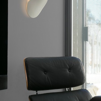 Cadeira de couro preto e luminária branca orgânica na parede