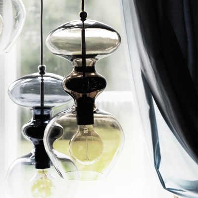 Lâmpadas penduradas em vidro transparente e preto com cortina cinzenta ao lado