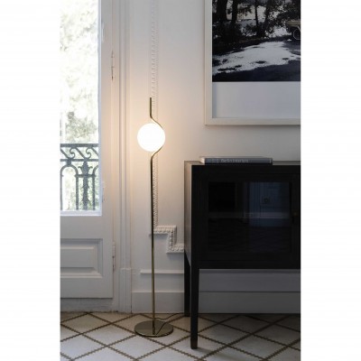 Candeeiro de pé com lâmpada redonda branca junto a porta e móvel negro