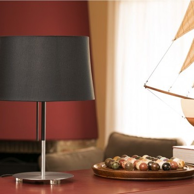 Candeeiro de mesa preto com base metálica junto a bolas de bilhar e modelo de barco numa sala