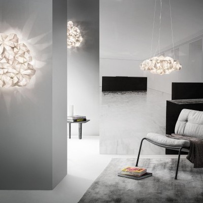 Lâmpadas modernas geométricas em ambiente minimalista com poltrona cinza e tapete