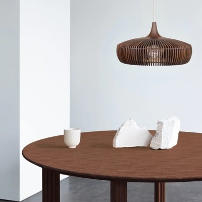 Mesa redonda de madeira com candeeiro pendente em madeira e objetos brancos em cima