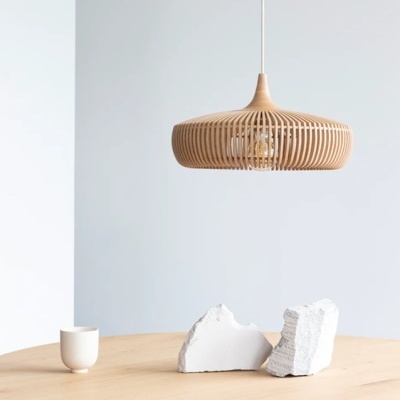 Candeeiro de teto de madeira pendente sobre mesa com pedras e chávena branca