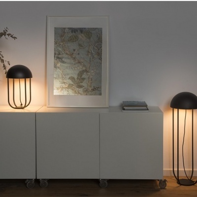 Móvel branco com rodas, duas lâmpadas pretas, arte botânica em moldura e vaso com ramos secos