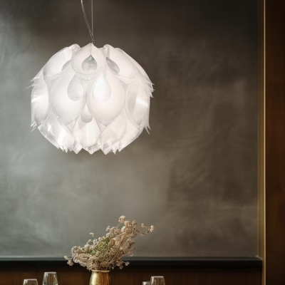 Lustre suspenso branco com pétalas sobre mesa de jantar com jarra dourada e flores secas