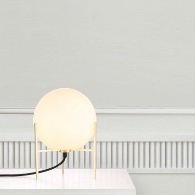 Candeeiro de mesa com cúpula branca esférica e estrutura dourada em mesa branca