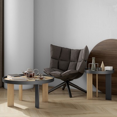 Mesas de centro em madeira clara e preto com cadeira acolchoada castanha escura num ambiente moderno