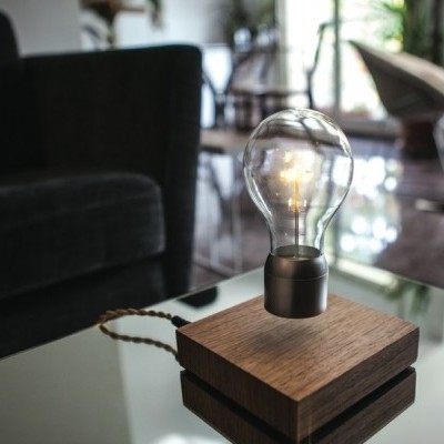 Candeeiro com base de madeira e lâmpada transparente sobre mesa de vidro